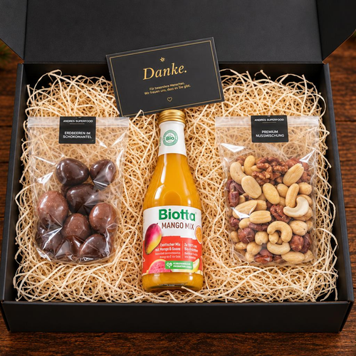 Grosse Geschenkbox von Andre’s Superfood mit 100 g Erdbeeren im Schokomantel, 100 g Premium-Nussmischung und Biotta Mango Mix – Weihnachtsgeschenk für Mitarbeitende und Kunden.