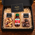 Kleine schwarze Geschenkbox von André’s Superfood mit Erdbeeren im Schokomantel, Premium-Nussmischung, Biotta Vital Shot Energy und Dankeskarte – Mitarbeiter- und Kundengeschenk.