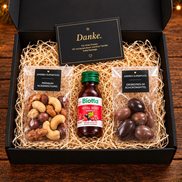 Kleine schwarze Geschenkbox von André’s Superfood mit Erdbeeren im Schokomantel, Premium-Nussmischung, Biotta Vital Shot Energy und Dankeskarte – Mitarbeiter- und Kundengeschenk.